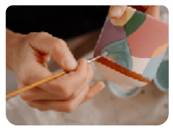 Manos pintando una pieza de cerámica con un pincel